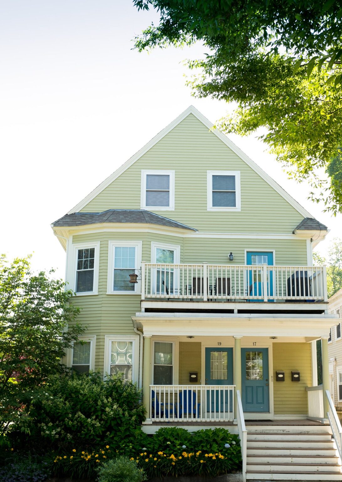 A green house with white balconies and a blue door.