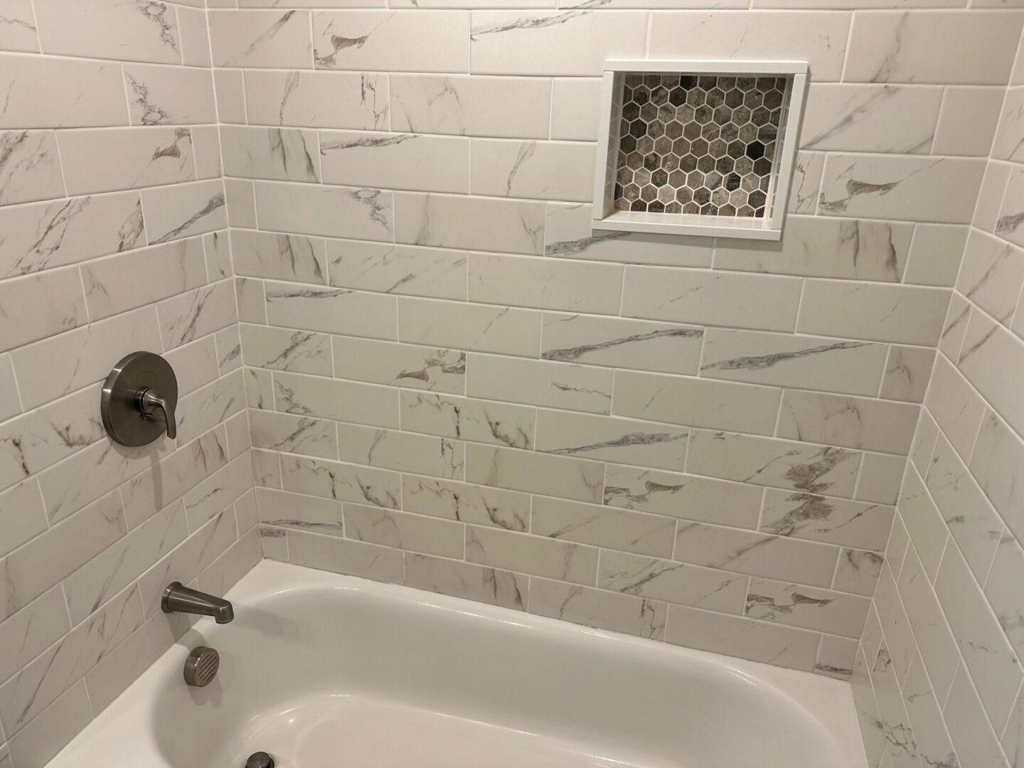 A bathroom with marble tile and white walls.