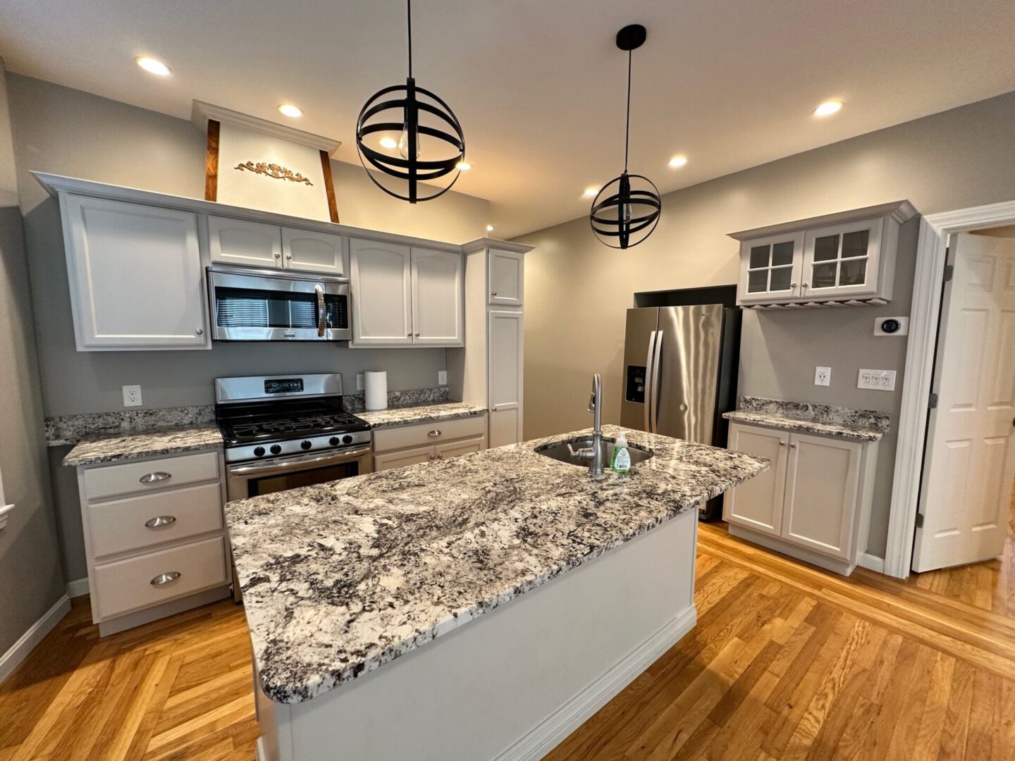 A kitchen with white cabinets and granite counter tops.